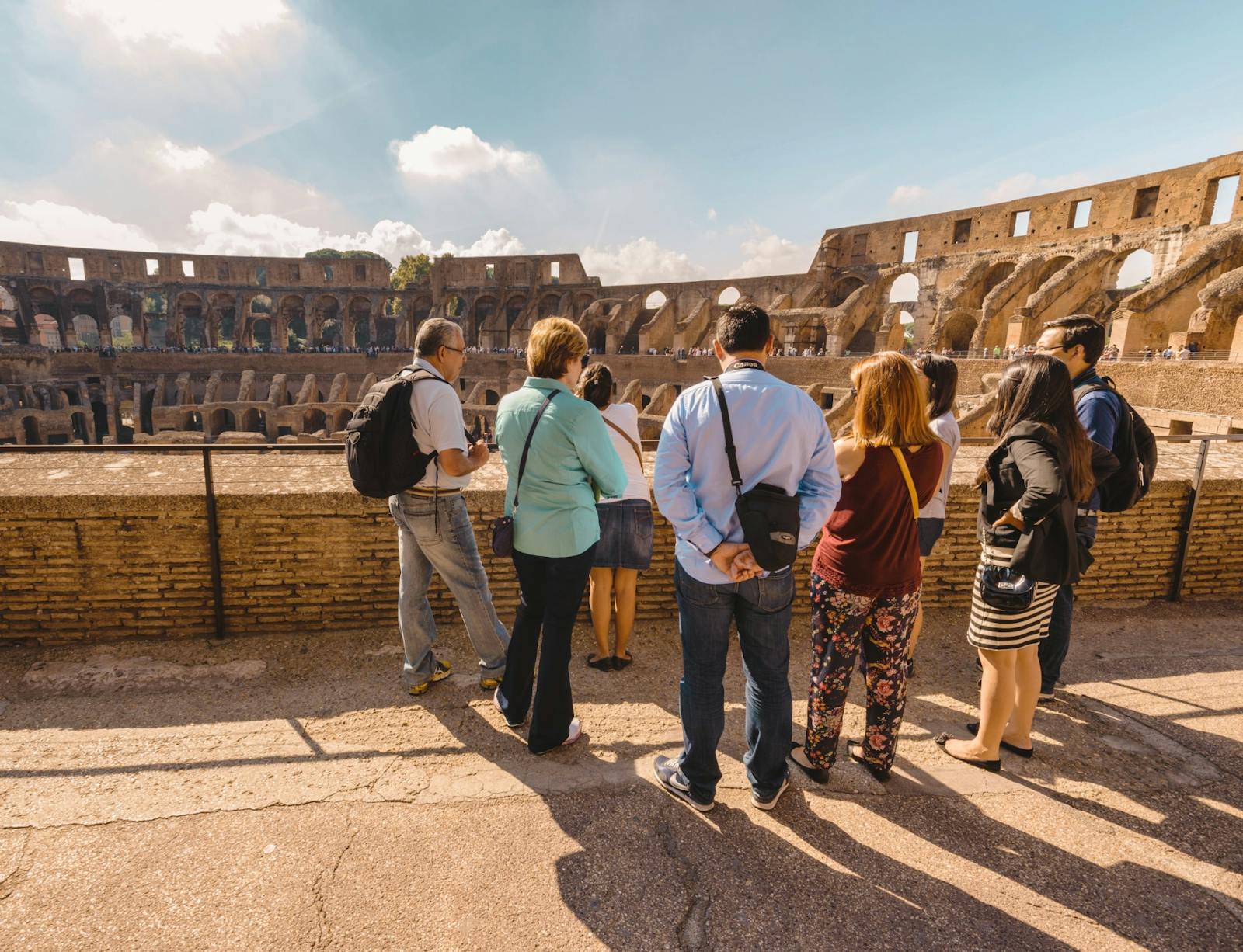 Turisti che osservano il Colosseo dalle gradinate soleggiate